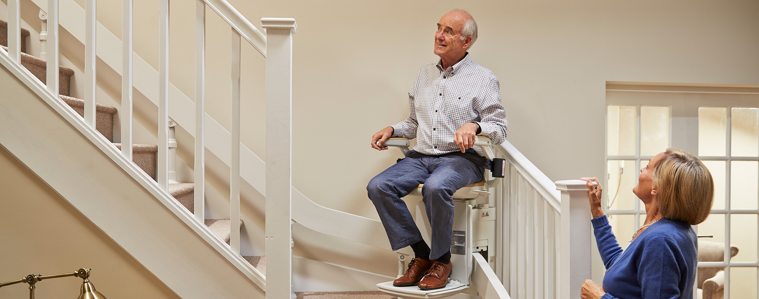 A man seated on an Acorn stairlift inside a home