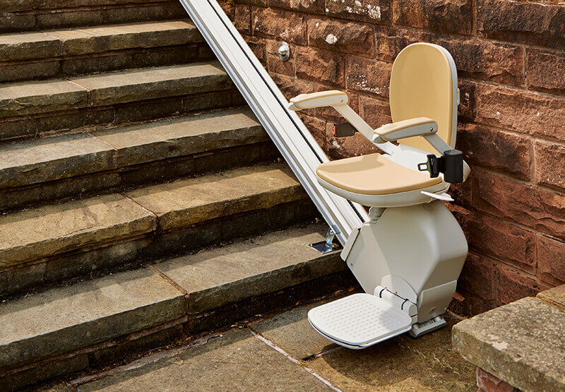 Acorn outdoor chair stairlift on exterior stone steps beside a garden